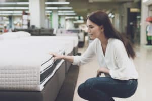 woman squatting looking at a mattress