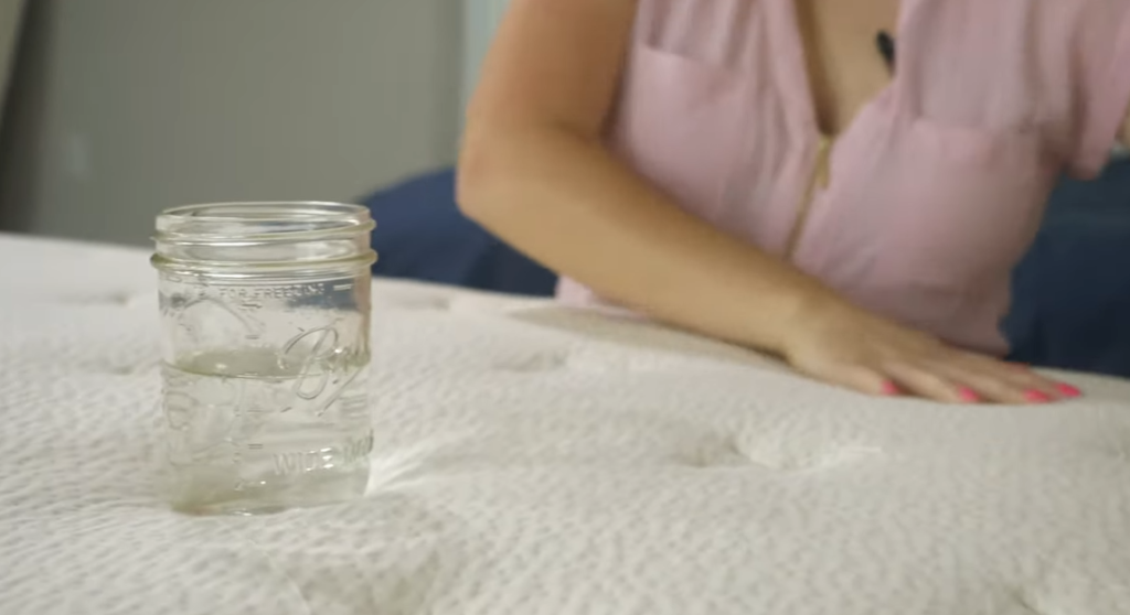 A glass of water sitting on the Birch Luxe mattress