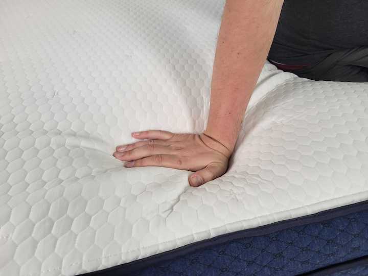 a man presses into the cover of the Aurora Luxe mattress