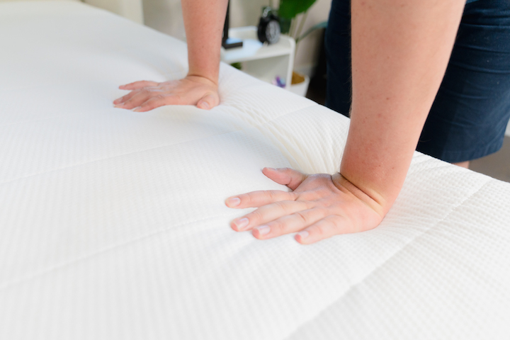 a man presses into the cover of the Helix Plus mattress