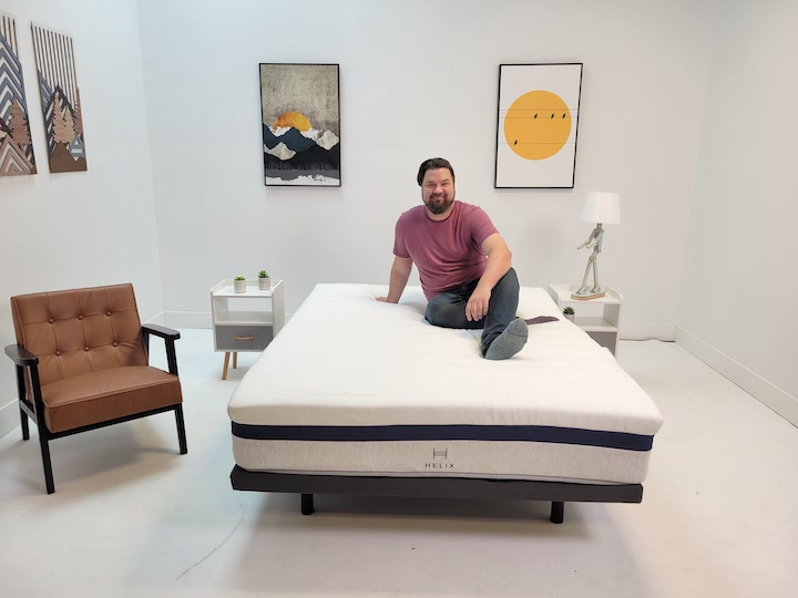 a man sits on top of the Helix Midnight mattress