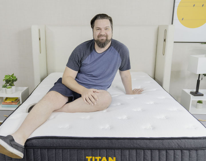 a man sits on top of the Titan Plus mattress