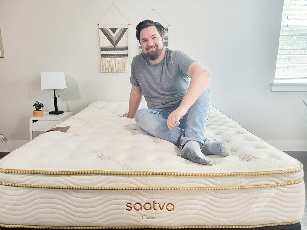 man sitting on the Saatva mattress and smiling