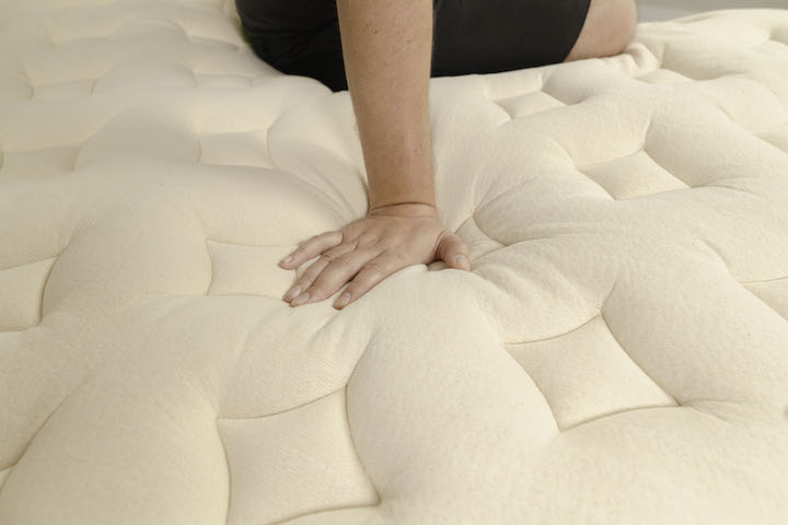 A man presses into the top of the Bear Natural mattress