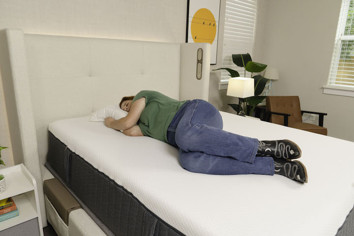 A woman sleeps on her side on the Emma Hybrid Cooling Elite mattress.