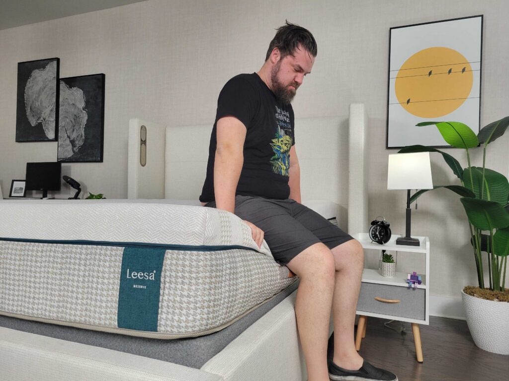 a man sits on the side of the Leesa Reserve mattress to test its edge support