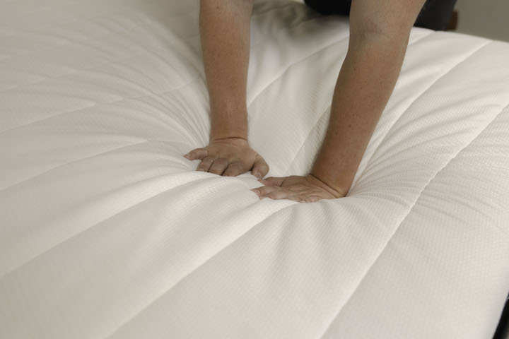 a man presses into the top of the Helix Midnight mattress