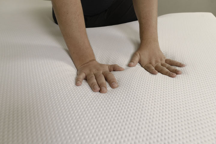 a man presses into the cover of the Purple Original mattress