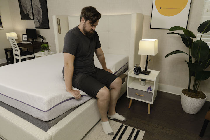 a man sits on the side of the Purple Original mattress