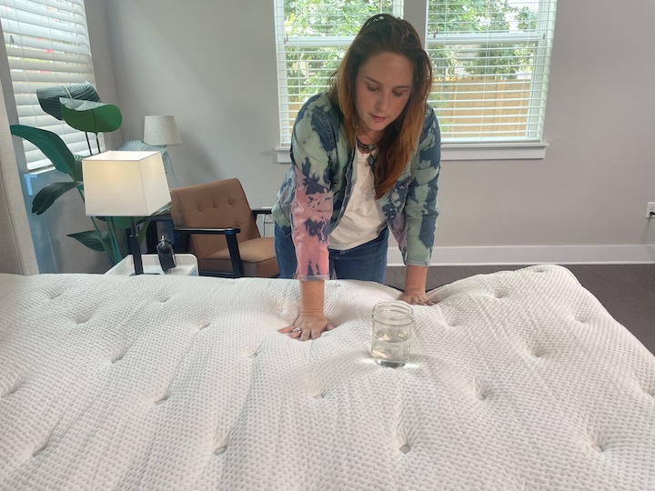 a woman tests motion transfer for the PlushBeds Signature Bliss mattress