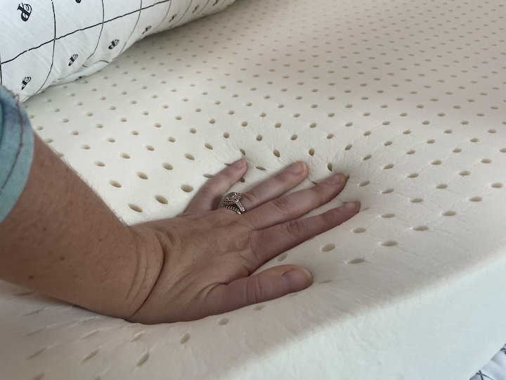 a woman presses into the latex layer of the PlushBeds Signature Bliss mattress