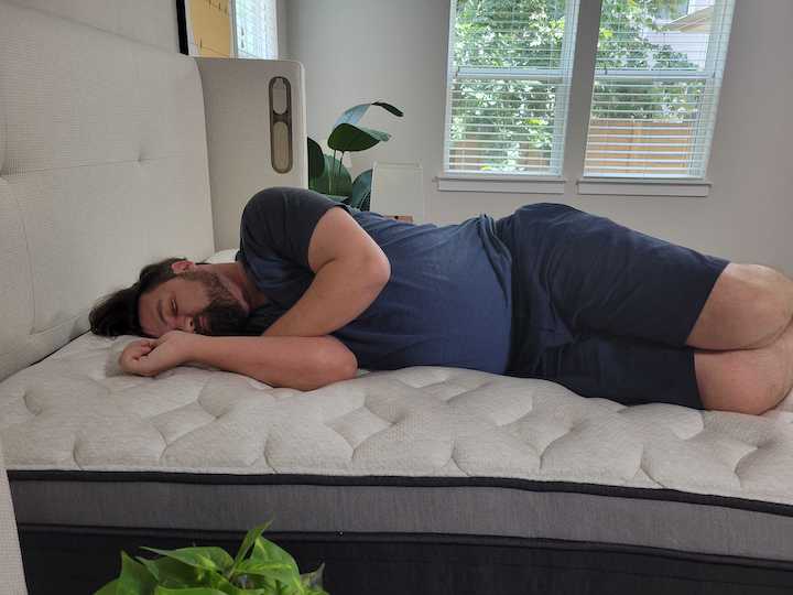 A man rests on his side on the Helix Plus Luxe