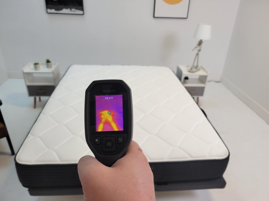 A man measuring the temperature of the plank mattress with a thermal imaging camera.