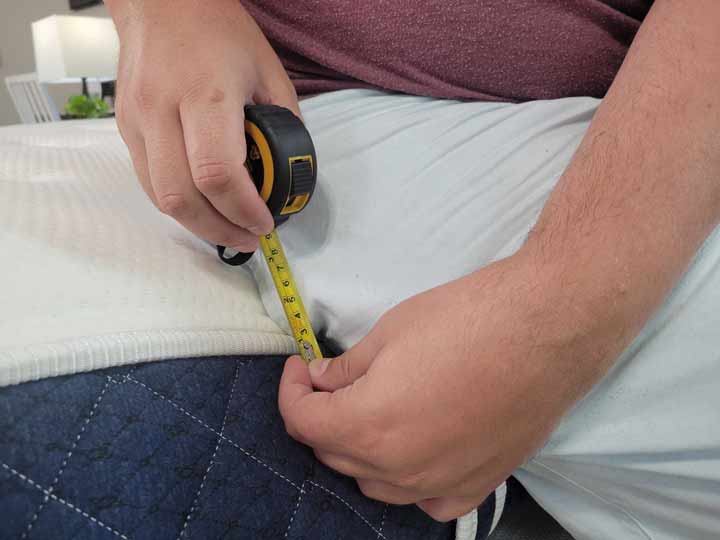 A close up image of a man holding a tape measure, showing how deep the sinkage of the edge is when sitting along the edge.