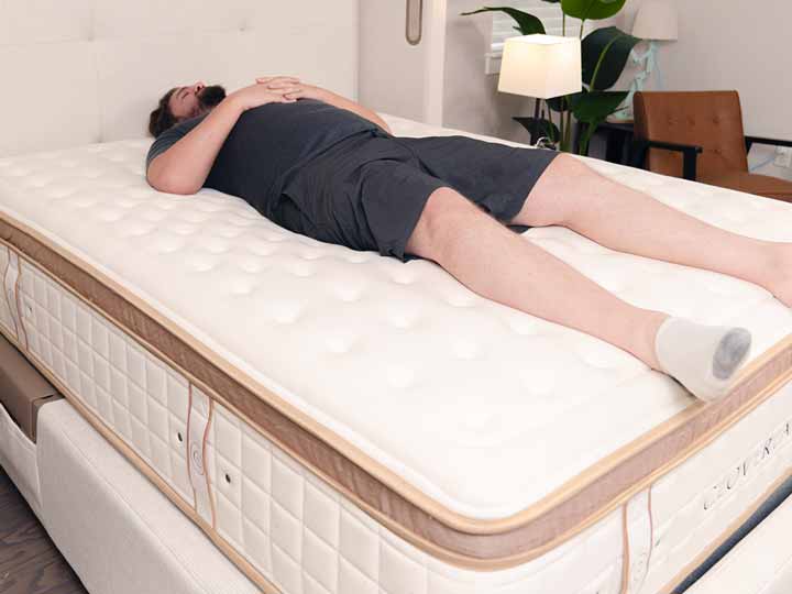 An image of a man resting on his back while on top of the Cloverlane Hybrid Mattress.