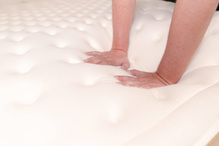 An image of two hands pressing into the surface of the Cloverlane Hybrid mattress.