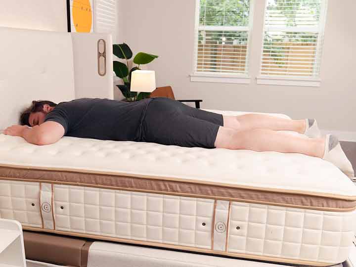 An image of a man resting on his stomach while on top of the Cloverlane Hybrid Mattress.