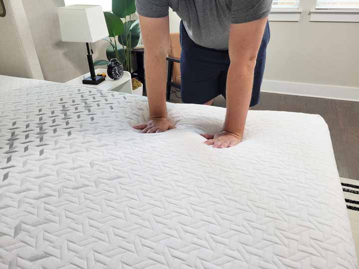 Another image of Marten pressing his hands into the top of the Nectar Premier Mattress.