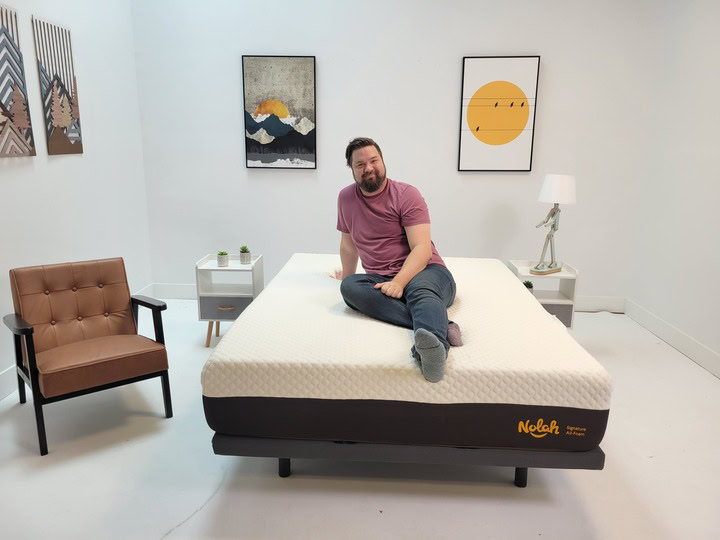 A man sits on top of the Nolah Signature 12" all-foam mattress